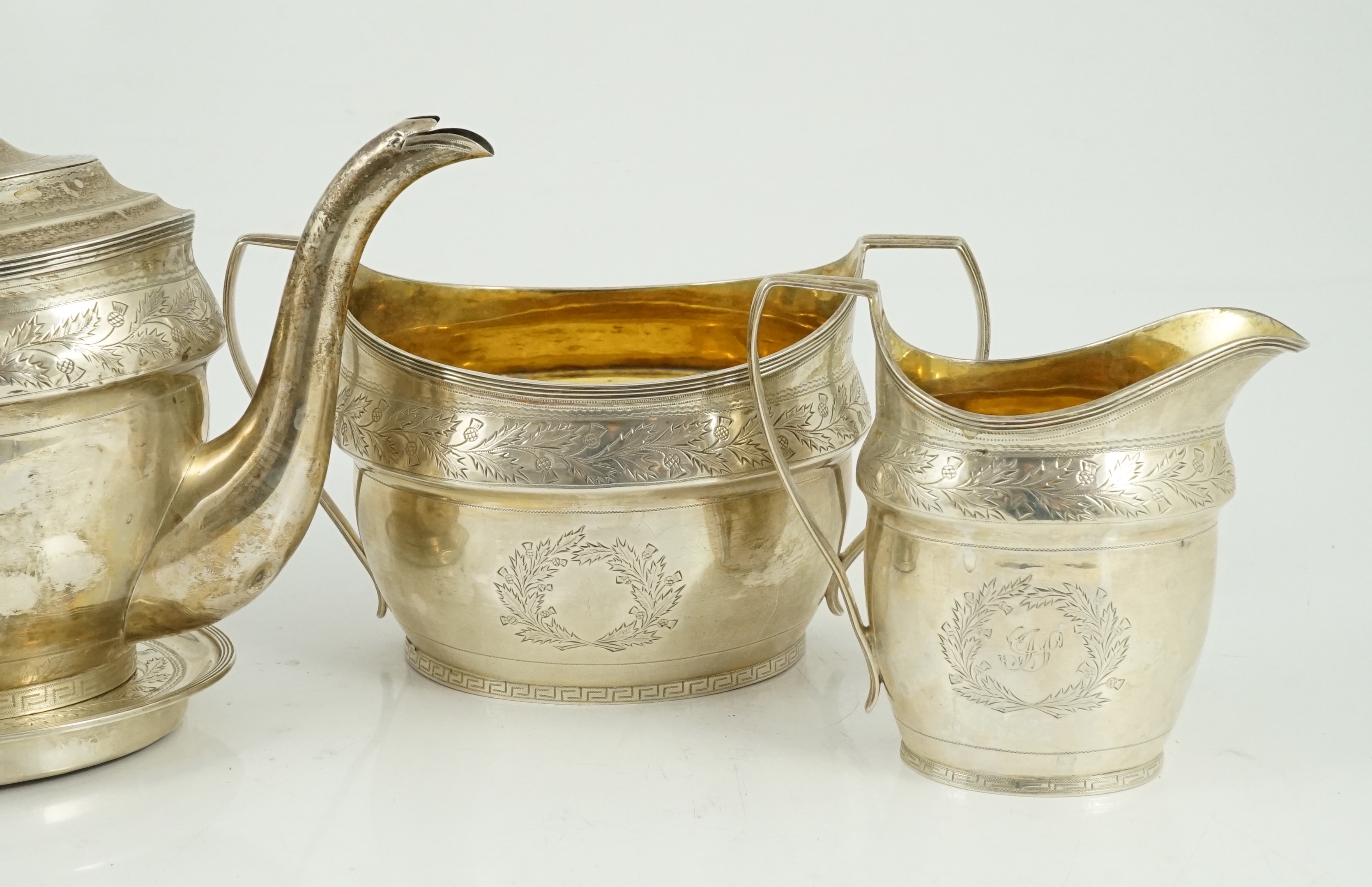 A George III Scottish chased silver oval three piece tea set and teapot stand, by William & Patrick Cunningham